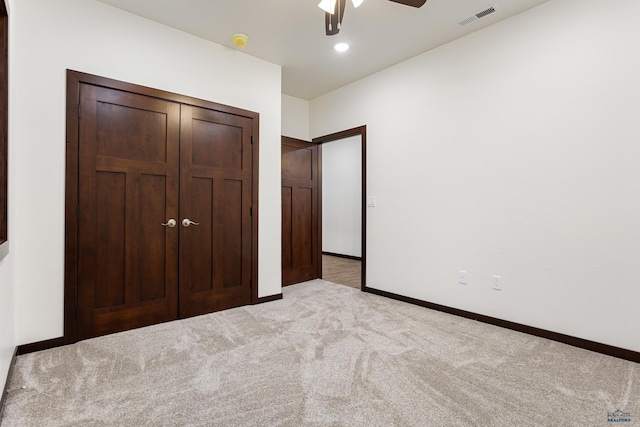 unfurnished bedroom featuring a closet, light colored carpet, visible vents, ceiling fan, and baseboards