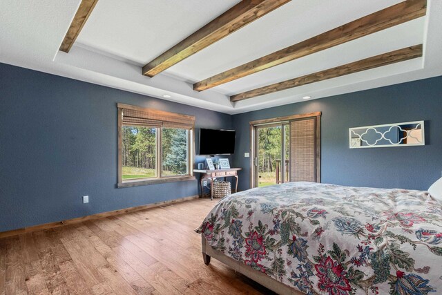 bedroom featuring wood-type flooring, beam ceiling, access to outside, and a tray ceiling