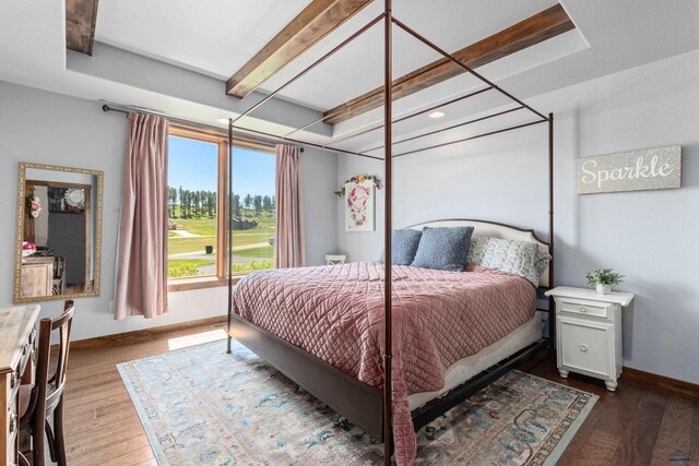 bedroom featuring a tray ceiling, hardwood / wood-style floors, and beam ceiling