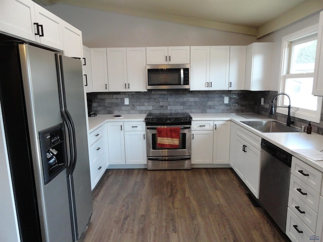 kitchen with white cabinetry, sink, dark wood-type flooring, stainless steel appliances, and vaulted ceiling