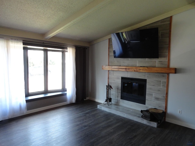 unfurnished living room featuring a fireplace, dark hardwood / wood-style flooring, a textured ceiling, and beamed ceiling