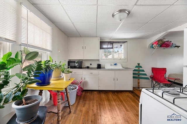 kitchen with a paneled ceiling, white cabinetry, hardwood / wood-style flooring, and electric range