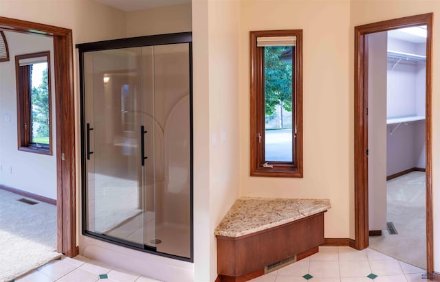 bathroom with a shower with door and tile patterned floors