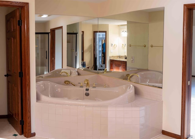 bathroom featuring tile patterned floors, a relaxing tiled tub, and vanity