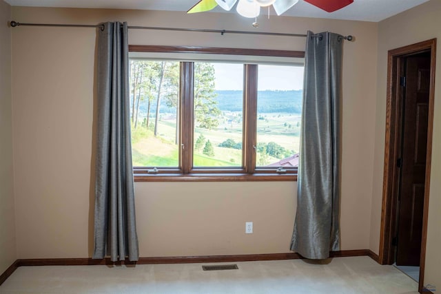 empty room featuring ceiling fan, a water view, and carpet flooring