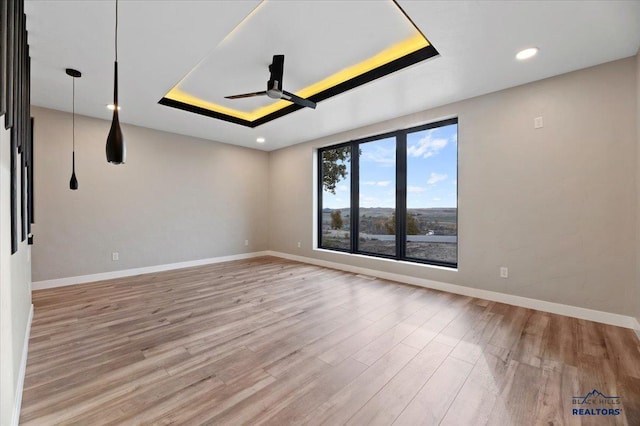 unfurnished room featuring baseboards, a ceiling fan, and a raised ceiling