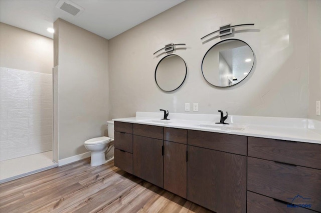 full bathroom with visible vents, a sink, toilet, and wood finished floors