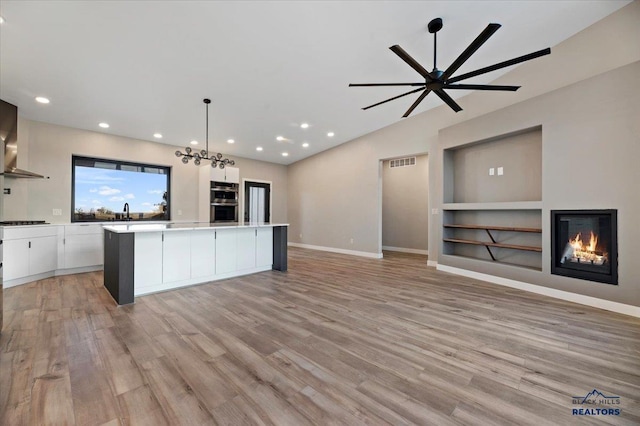 kitchen with a glass covered fireplace, white cabinets, and light wood-type flooring