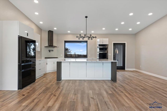 kitchen featuring freestanding refrigerator, wall chimney exhaust hood, modern cabinets, white cabinets, and stainless steel double oven