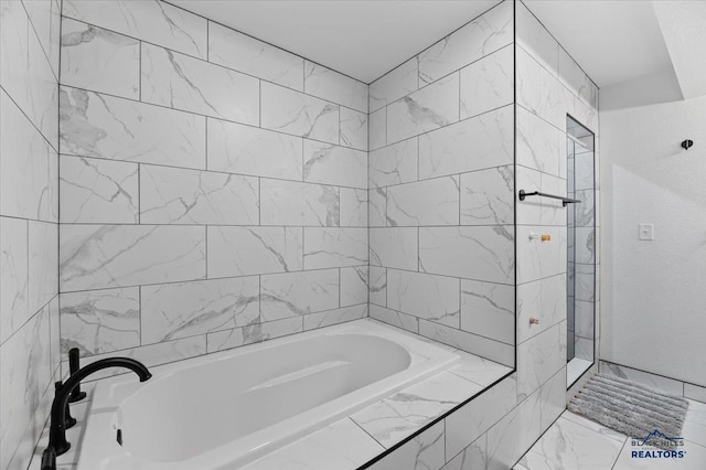 bathroom featuring marble finish floor and a tub