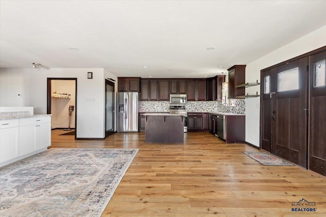 kitchen with appliances with stainless steel finishes, light countertops, dark brown cabinetry, and tasteful backsplash