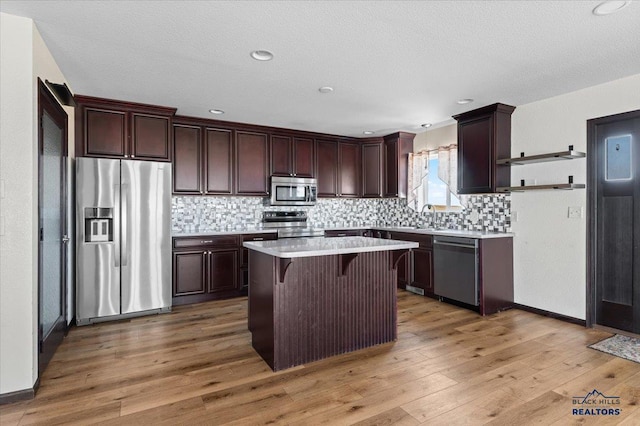 kitchen with a center island, open shelves, stainless steel appliances, light countertops, and a kitchen bar