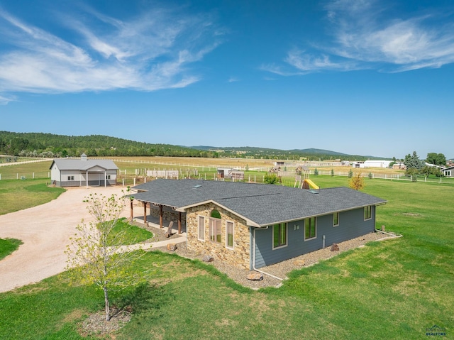 view of front of home featuring a front lawn, a rural view, and a garage