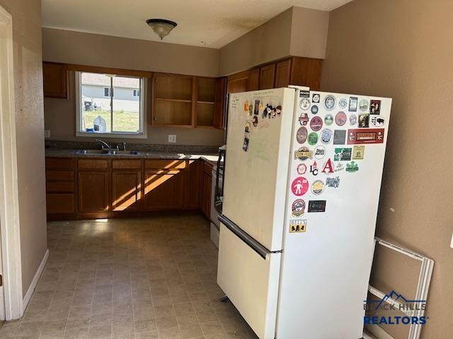 kitchen with sink, white refrigerator, stove, and light tile patterned flooring