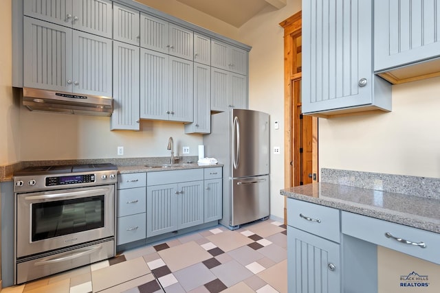 kitchen featuring light tile patterned flooring, sink, stainless steel appliances, and light stone counters