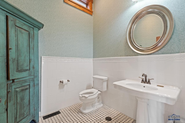 bathroom with backsplash, toilet, tile patterned flooring, and tile walls