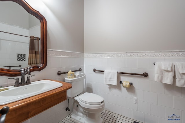 bathroom featuring sink, toilet, tile patterned flooring, and tile walls