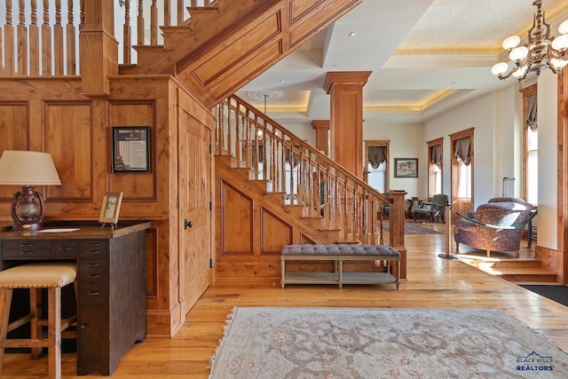 stairs featuring a notable chandelier, ornamental molding, hardwood / wood-style floors, and ornate columns