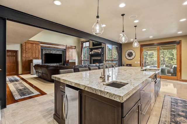 kitchen with light tile patterned floors, sink, a healthy amount of sunlight, and an island with sink