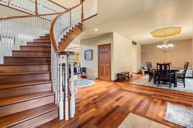 stairway with wood-type flooring, a notable chandelier, and a textured ceiling