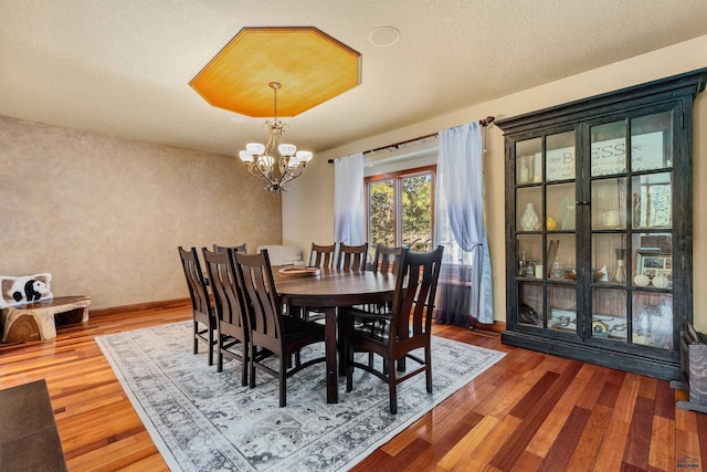 dining space featuring a notable chandelier, a textured ceiling, and hardwood / wood-style floors