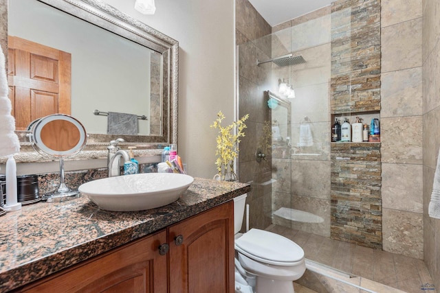 bathroom featuring tiled shower, toilet, and vanity