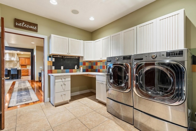 laundry area featuring washer and dryer, light hardwood / wood-style flooring, and cabinets