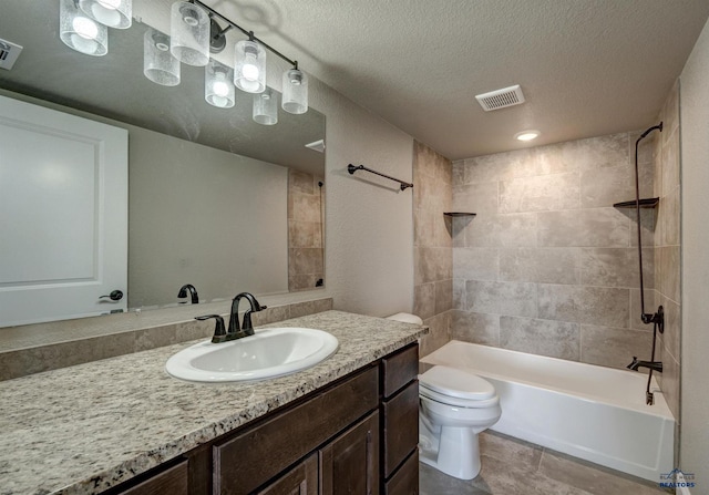 full bathroom with tile patterned floors, tiled shower / bath combo, a textured ceiling, vanity, and toilet