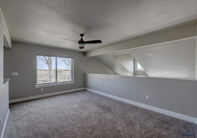 carpeted spare room featuring a textured ceiling, ceiling fan, and vaulted ceiling with beams