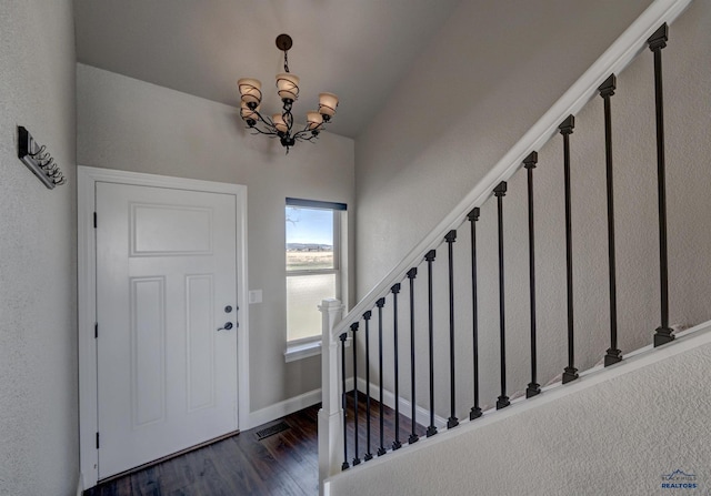 entryway with dark wood-type flooring and a chandelier