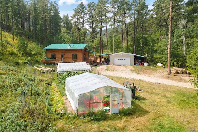 exterior space featuring a garage, a wooden deck, an outdoor structure, and a lawn