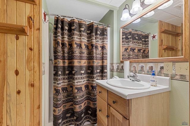 bathroom featuring a paneled ceiling, vanity, and walk in shower