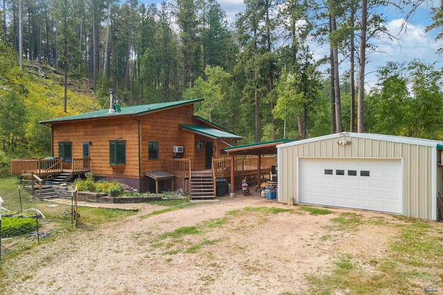 exterior space with a deck, a garage, and an outbuilding