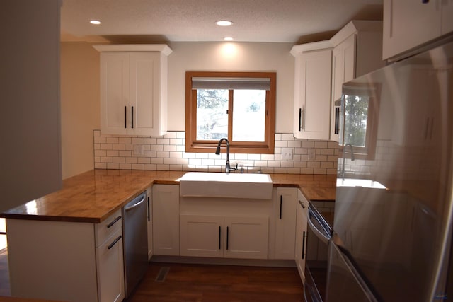 kitchen featuring dark hardwood / wood-style floors, stainless steel appliances, sink, decorative backsplash, and white cabinetry