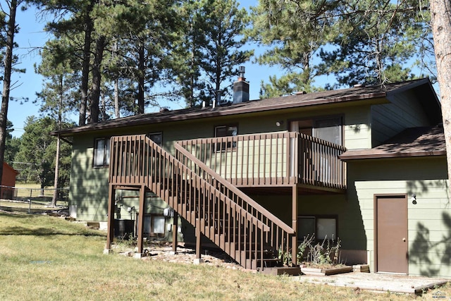 back of property with a yard and a wooden deck