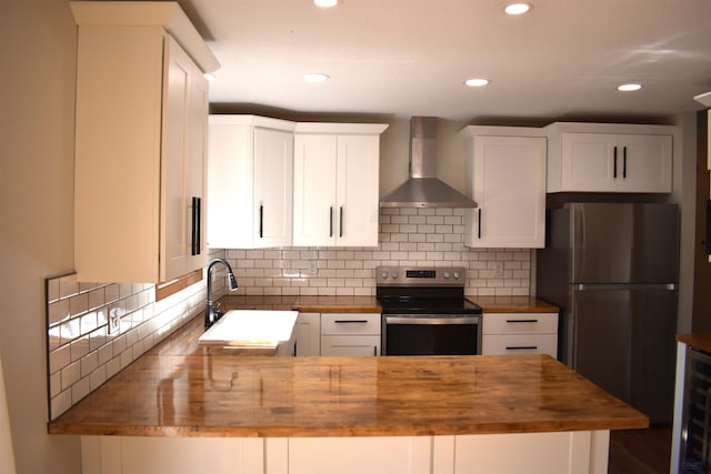 kitchen featuring stainless steel appliances, white cabinetry, wall chimney exhaust hood, wooden counters, and tasteful backsplash