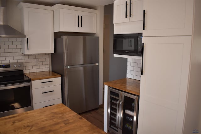 kitchen with wooden counters, backsplash, stainless steel appliances, and wall chimney range hood