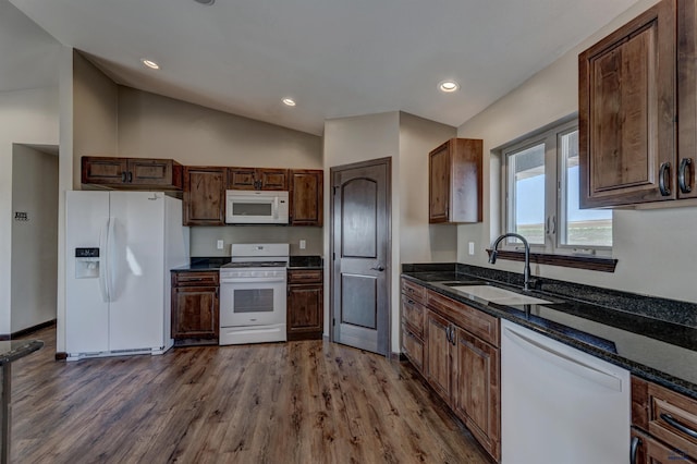 kitchen with vaulted ceiling, white appliances, hardwood / wood-style floors, sink, and dark stone counters