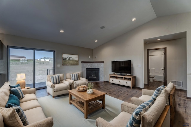 living room with vaulted ceiling, hardwood / wood-style flooring, and a tile fireplace