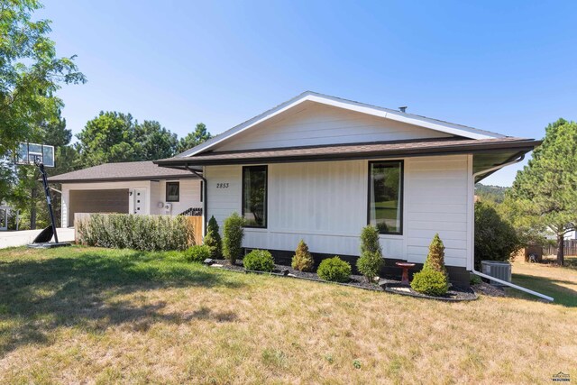 ranch-style home with central AC unit, a garage, and a front lawn