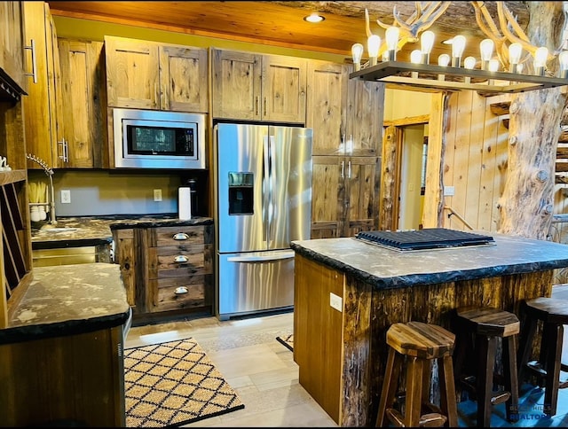 kitchen featuring a center island, wooden ceiling, brown cabinetry, stainless steel appliances, and a breakfast bar area