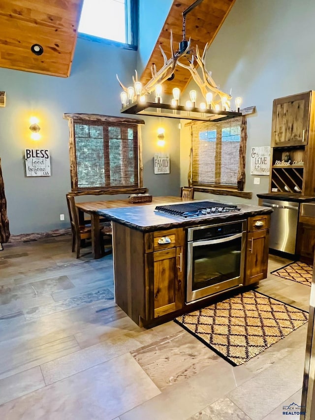 kitchen featuring stainless steel appliances, a high ceiling, an inviting chandelier, and dark countertops