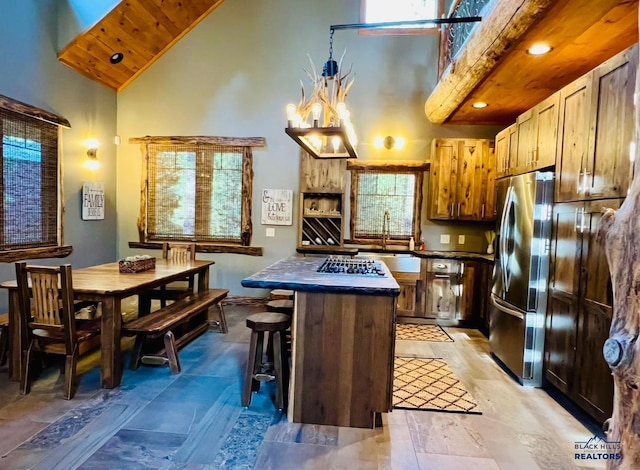 kitchen featuring high vaulted ceiling, freestanding refrigerator, a kitchen breakfast bar, a sink, and dark countertops