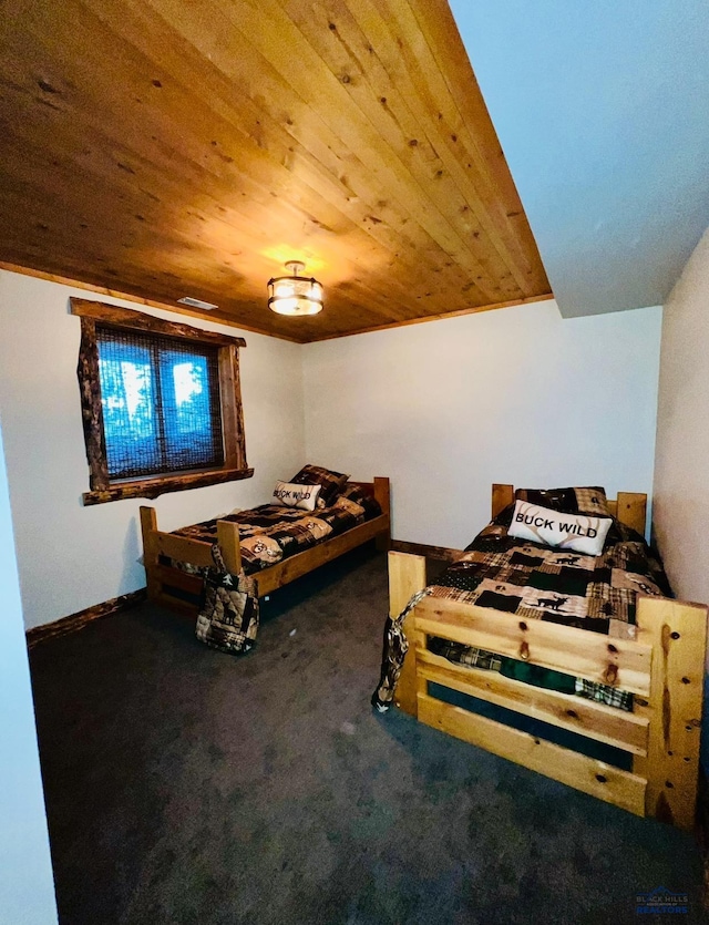 bedroom with baseboards, wooden ceiling, and carpet