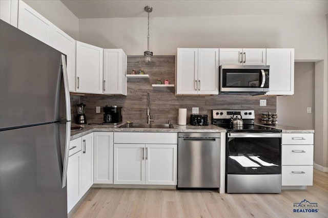 kitchen featuring appliances with stainless steel finishes, white cabinetry, light hardwood / wood-style flooring, and sink