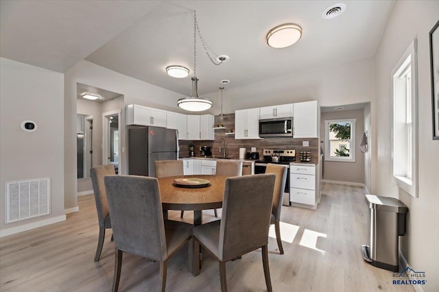 dining space with sink and light hardwood / wood-style floors