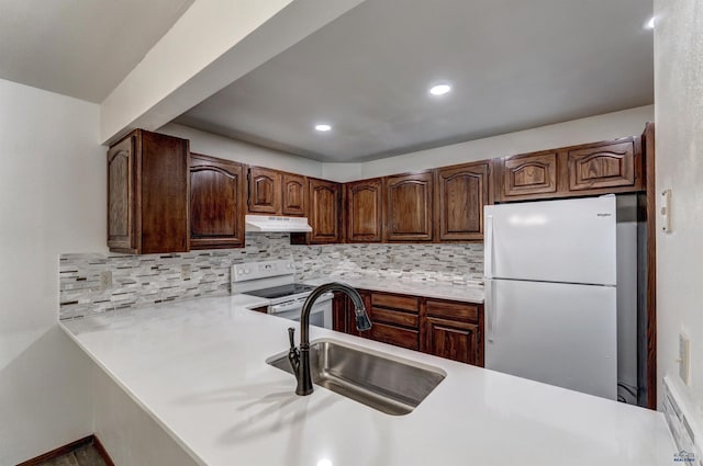 kitchen with white appliances, kitchen peninsula, sink, and tasteful backsplash