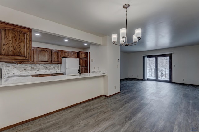 kitchen featuring white fridge, pendant lighting, wood-type flooring, tasteful backsplash, and a chandelier