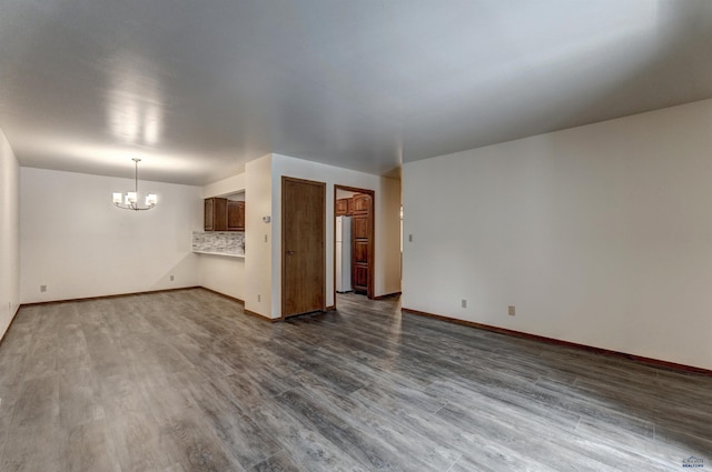 unfurnished living room featuring dark hardwood / wood-style flooring and an inviting chandelier