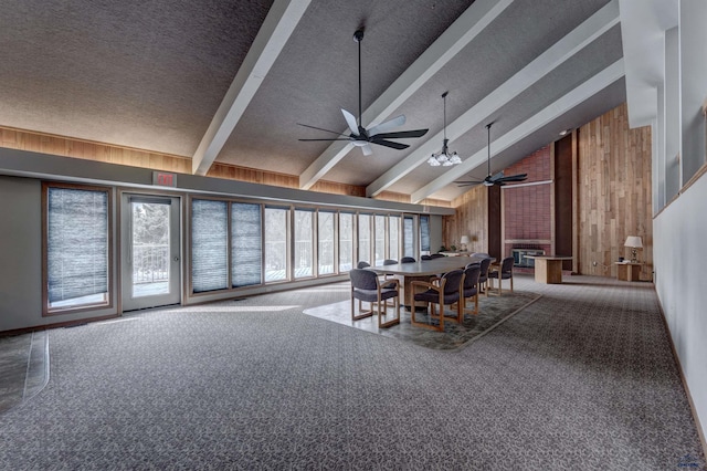 carpeted dining room with beamed ceiling, high vaulted ceiling, wooden walls, a textured ceiling, and ceiling fan